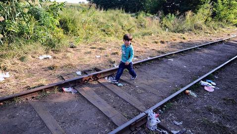 Siguiendo a su familia, un niño camina solo por las vías del tren cerca del pueblo de Roszke, en la frontera entre Serbia y Hungría
