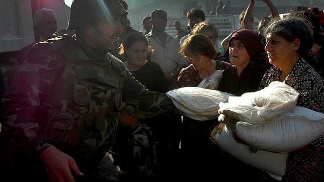 Un militar de Assad reparte ayuda entre los habitantes de Qusair este miércoles