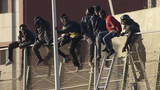 Un guardia civil intenta convencer a un grupo de subsaharianos encaramados a la valla para que depongan su actitud