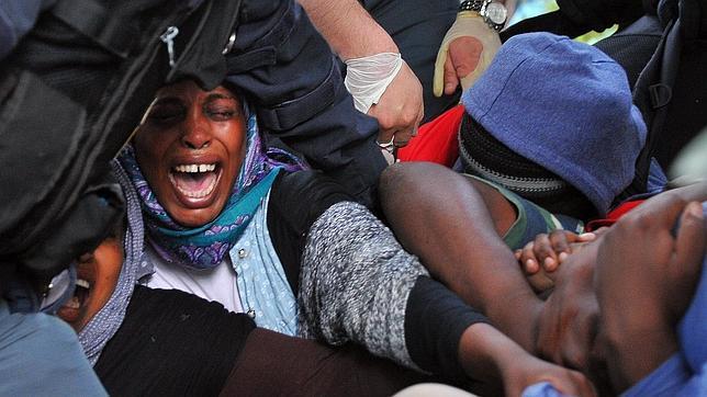 Inmigrantes indocumentados forcejean con los agentes de policía para evitar ser desalojados de los bajos de un puente ferroviario en la localidad fronteriza de Ventimiglia (Italia)