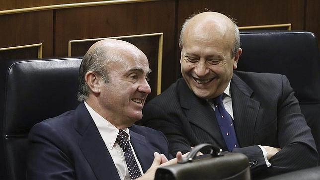 José Ignacio Wert hablando con el ministro de Economía, Luis de Guindos, durante la sesión de control al Gobierno