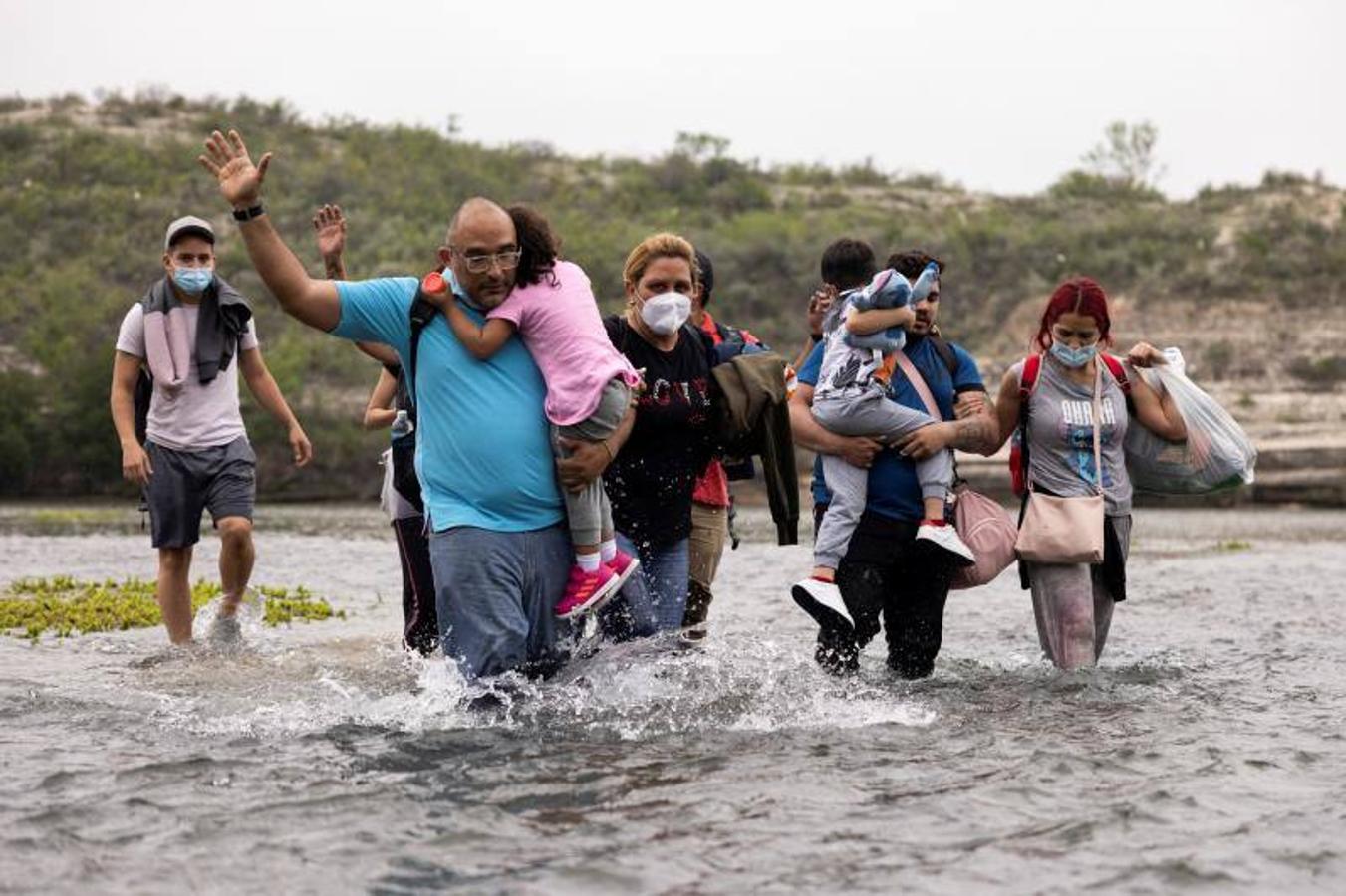 Con los niños en brazos y cargados con sus pertenencias, el grupo intenta cruzar el río