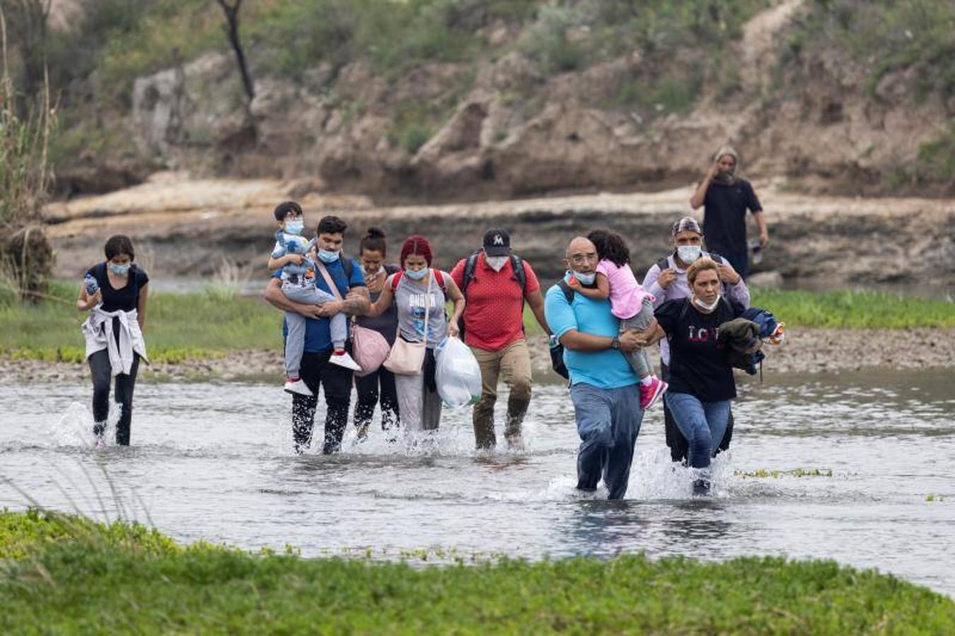 Un grupo numeroso de venezolanos vadea el río para llegar al otro lado de la frontera