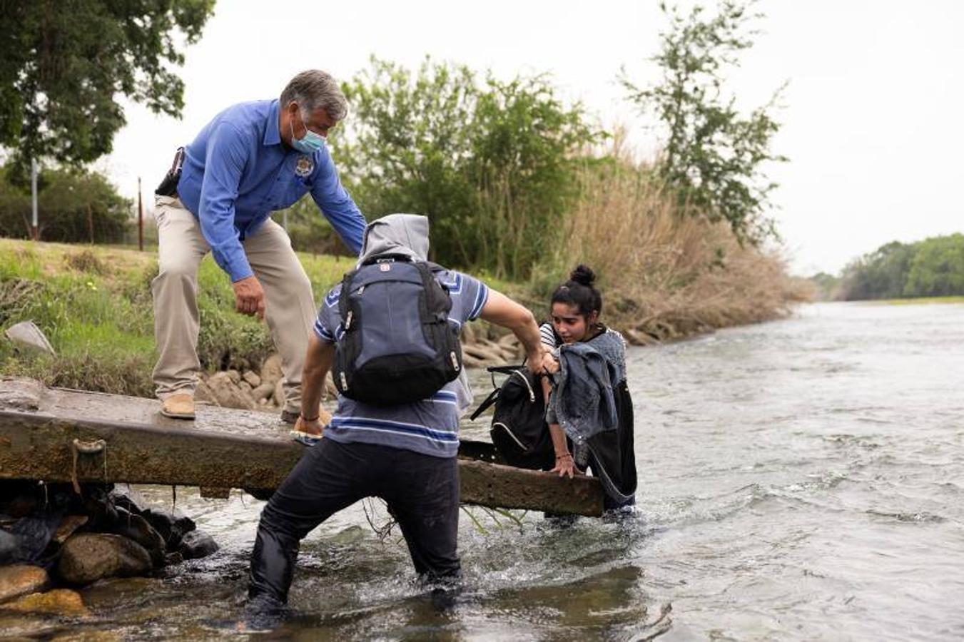Un agente y un inmigrante ayudan a una joven a salir del agua