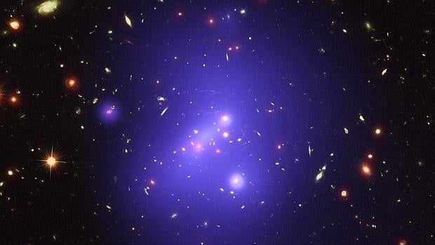 Esta imagen del cúmulo IDCS 1426 es una composición de los datos de tres instrumentos que observan en diferentes longitudes de onda: rayos X del telescopio espacial Chandra (en azul), luz visible del Hubble (en verde), e infrarrojos del Spitzer (en rojo)