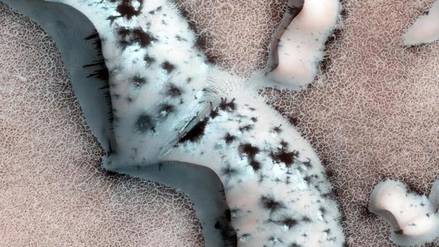 El hielo polar de Marte es una combinación de agua y CO2. Igual que en su forma gaseosa, el CO2 congelado permite el paso de la luz solar, pero no el de su calor. Y eso provoca, en los veranos, un "efecto invernadero de estado sólido" que crea focos de calentamiento, que en la imagen se ven como puntos negros en el hielo