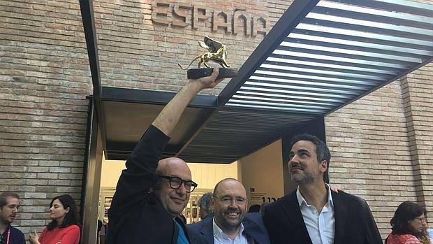 Carnicero y Quintáns posan sonrientes con el León de Oro en el exterior del Pabellón Español