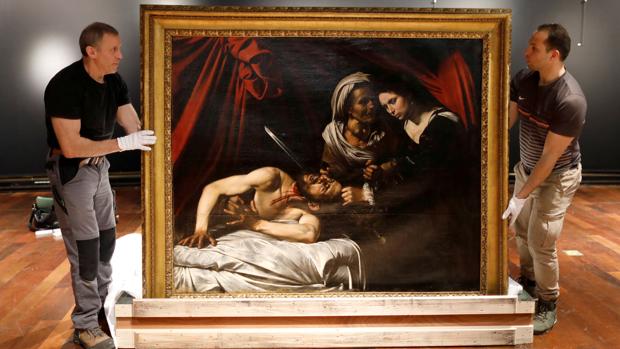 Dos operarios colocan la obra obra «Judith y Holofornes», atribuida a Caravaggio