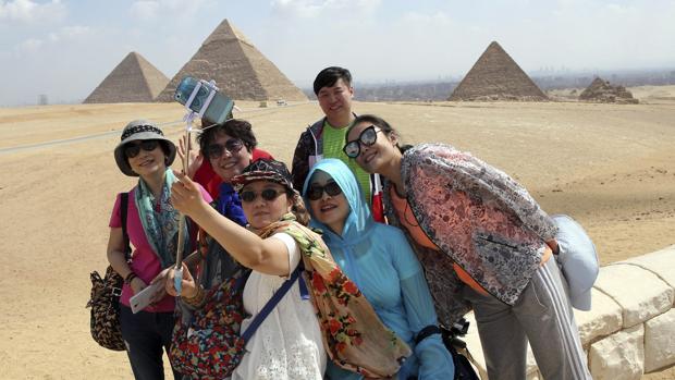 Un grupo de turistas se hace un selfie frente a las pirámides de Guiza, en Egipto