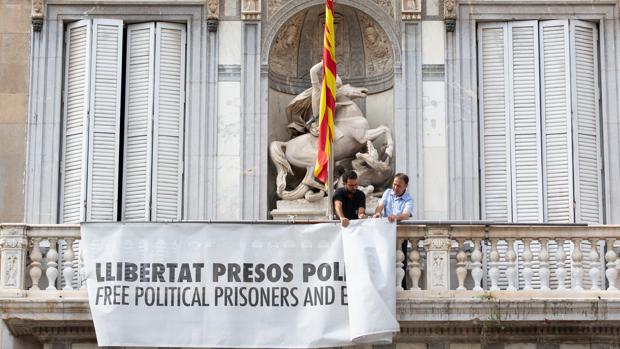 Momento en que la pancarta con el lazo amarillo en honor a los presos del «procés» se retiró de la fachada de la Generalitat
