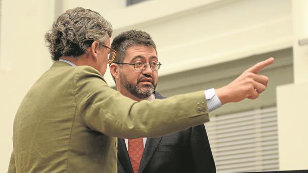 El secretario del Pleno indica ayer a Sánchez Mato cuál es su nuevo asiento en el hemiciclo
