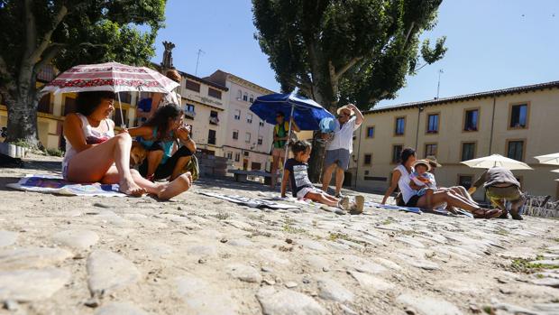 Varias personas con toallas y sombrillas protestan por la remodelación de la Plaza del Grano de León
