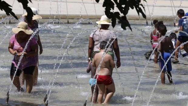 Gente se refresca en una fuente durante la ola de calor
