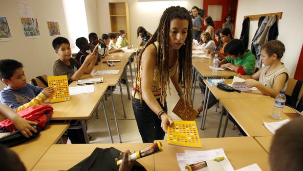 Una profesora reparte material a los alumnos en una escueka de Vic