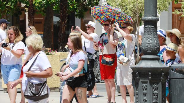 Imagen de archivo de unos turistas en Valencia protegiéndose del sol