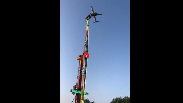 Un avión pasando cerca de la atracción de feria instalada en el municipio de Culleredo
