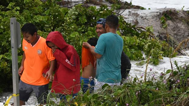 Unos niños se alejan luego de ser golpeados por las olas que causa el huracán Dorian, en Bahamas