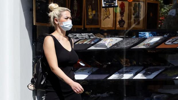 Una mujer pasea por Alicante con mascarilla en una zona de comercios