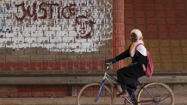Una niña pasa junto a un grafiti que pide «justicia» junto a un retrato del asesinado expresidente Thomas Sankara en Uagadugú, Burkina Faso