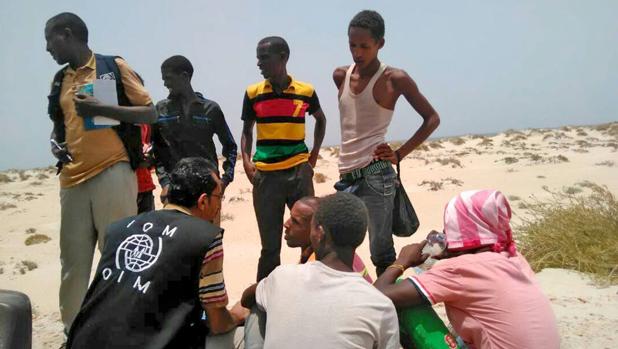 Un trabajador de la Organización Internacional para las Migraciones ayuda a migrantes que fueron obligados a arrojarse al mar en una una playa en shabua (Yemen)