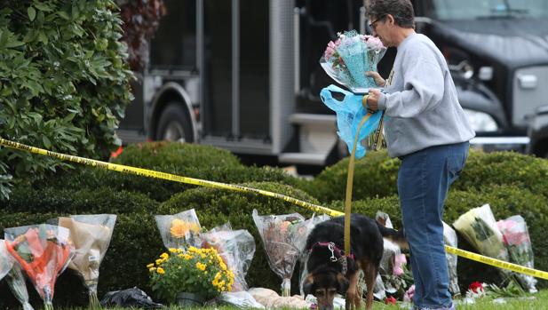 Una mujer lleva unas flores al memorial de la sinagoga