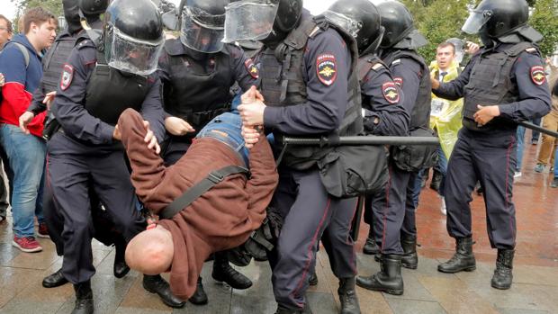 Varios policías antidisturbios se llevan en volandas a un manifestante durante una protesta opositora en el centro de Moscú