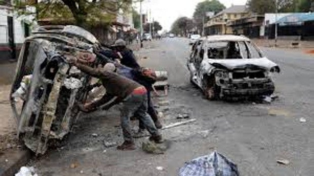 Recolectores de chatarra recuperan una carcasa de un automóvil quemado durante los ataques xenófobos en Johannesburgo, Sudáfrica.