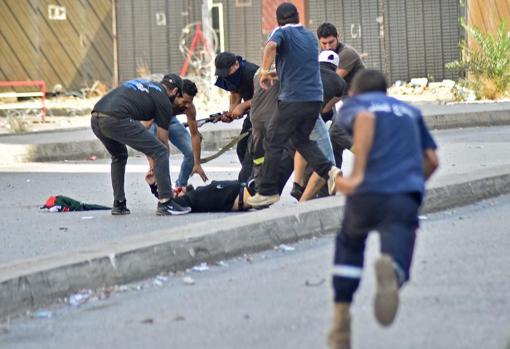 An injured person during the demonstration lies on the approach while several people help him