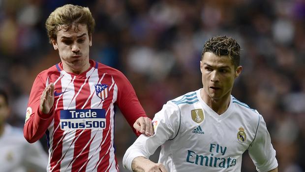 El futbolista del Atlético de Madrid Antoine Griezmann corre ante la mirada de Cristiano Ronaldo