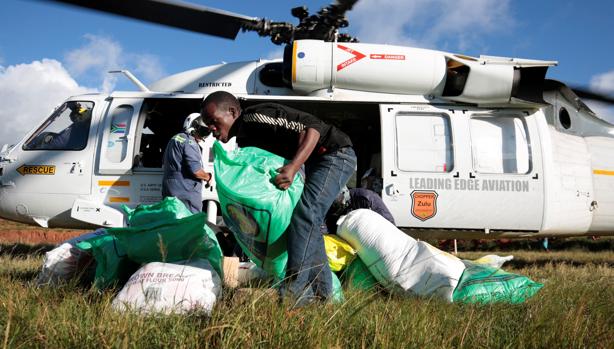 Varias personas bajan de un helicóptero sacos con ayuda humanitaria destinados a los afectados por el ciclón Idai, este viernes en Ngangu (Zimbabue)