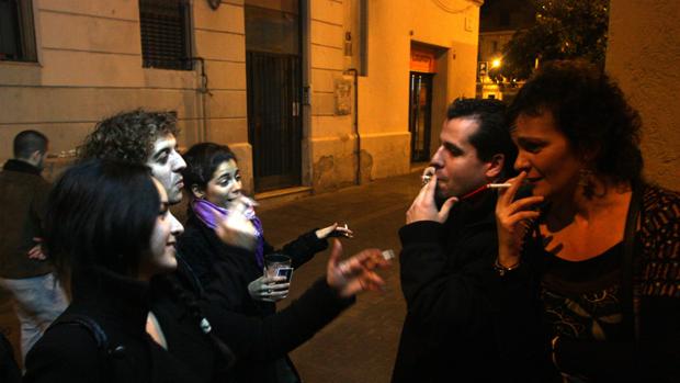 Jóvenes fumando en la puerta de un bar