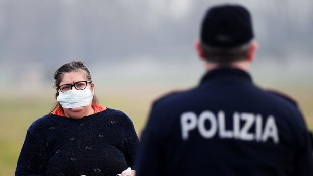 Una mujer con una mascarilla conversa con un policía en el norte de Italia